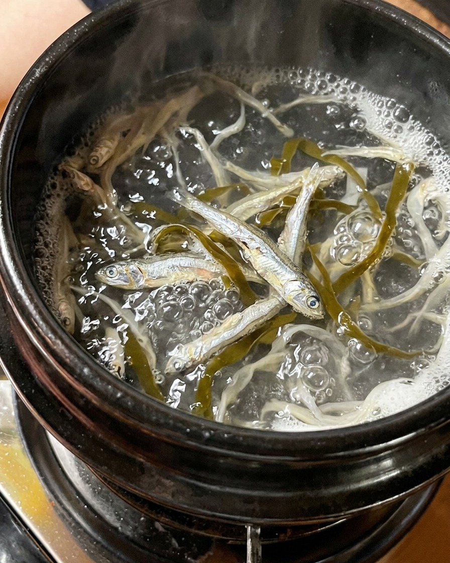 Petits anchois séchés et morceaux dalgue bouillant dans une casserole deau.