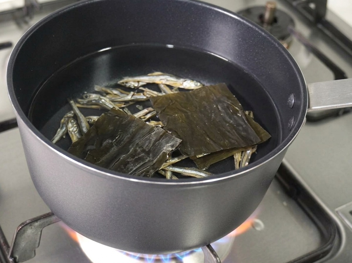 Anchois séchés et un morceau carré de varech séché flottant dans la casserole deau.