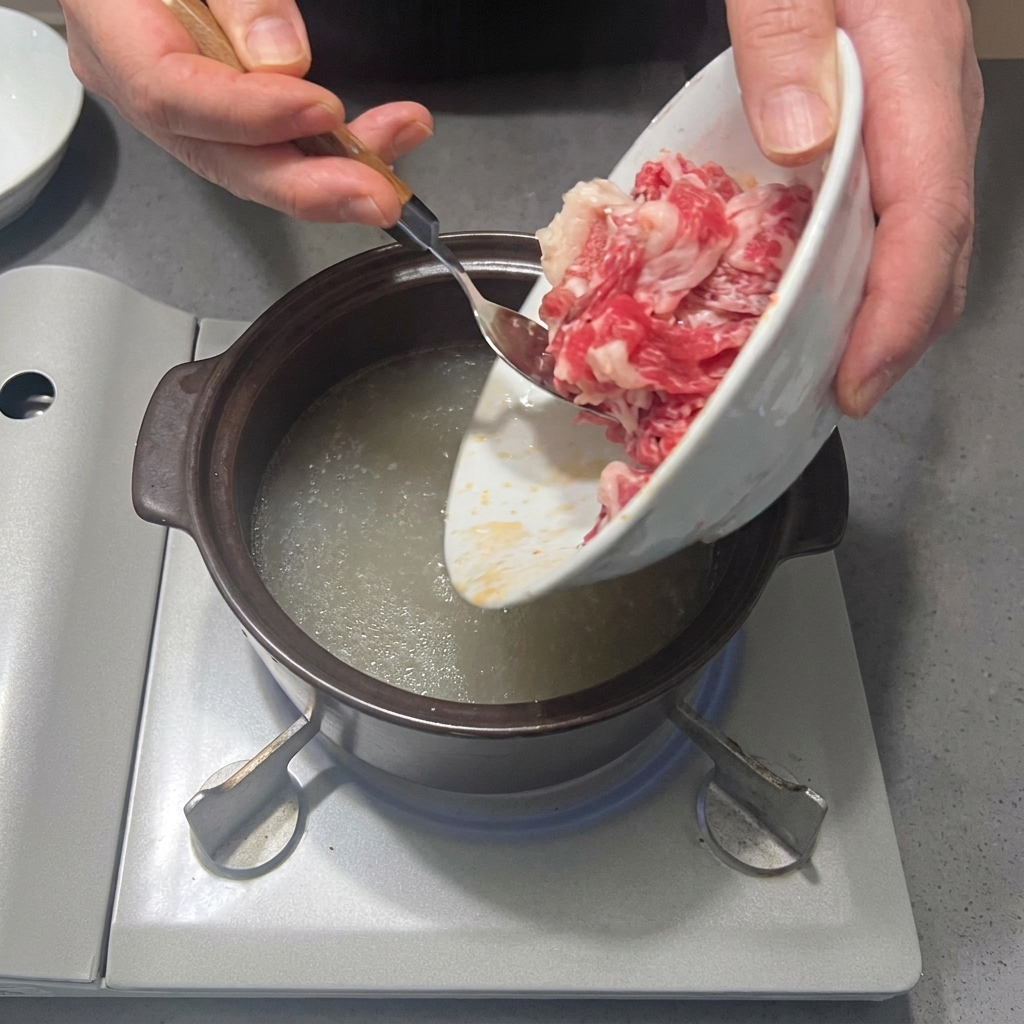 De fines tranches de poitrine de bœuf fraîche ajoutées dans le bouillon assaisonné.