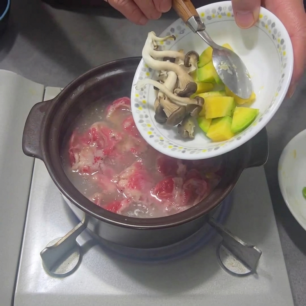 Tranches de champignons et de courgette ajoutées au ragoût frémissant.