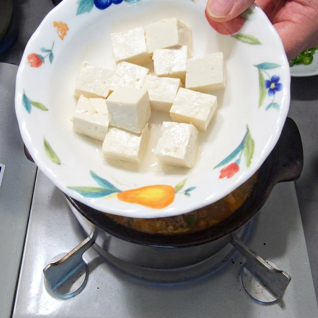 Dés de tofu soyeux et blanc ajoutés délicatement dans le ragoût frémissant.