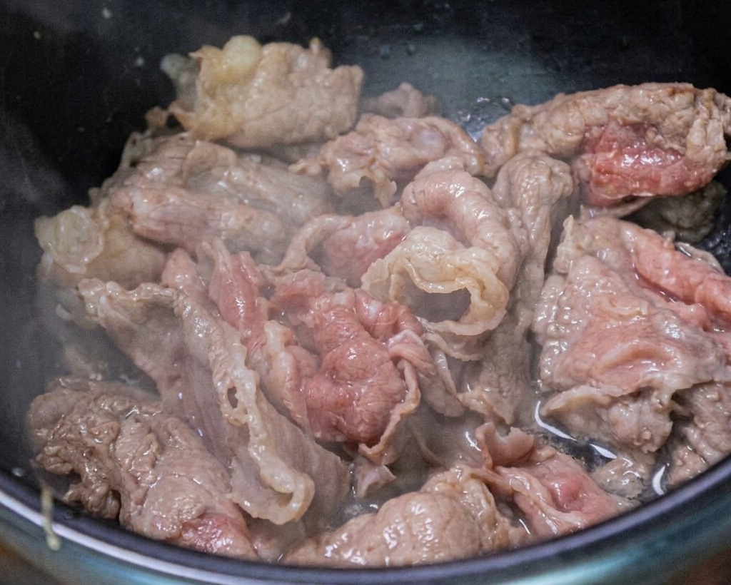 Bœuf sauté dans le pot avec de lail émincé et des oignons verts.