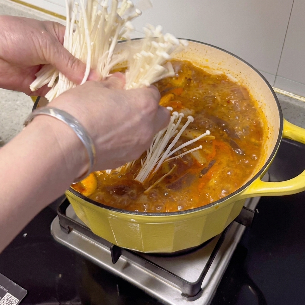 Champignons enoki, cébettes et piments frais disposés sur le ragoût.