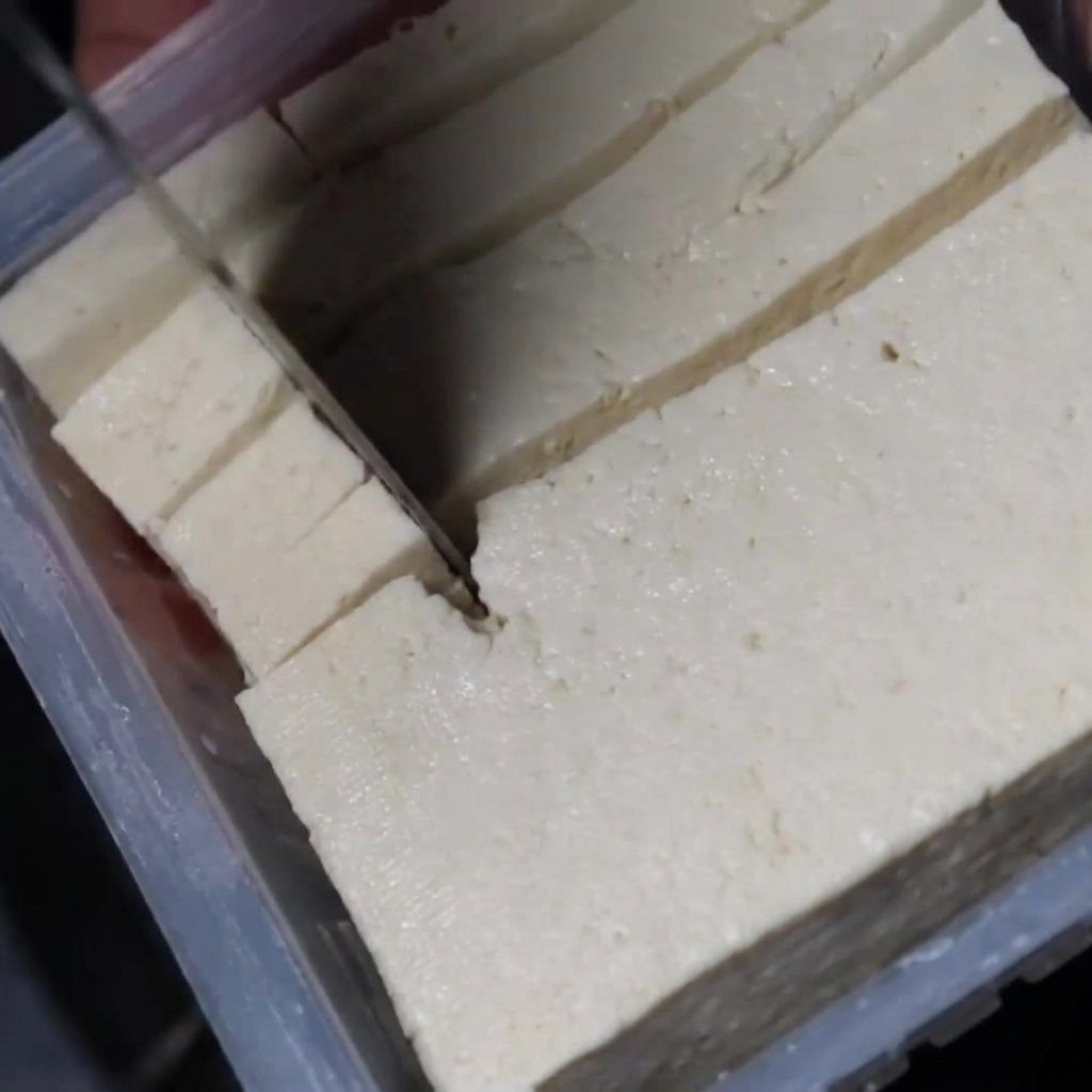 Des cubes de tofu blanc plongés dans le ragoût frémissant.