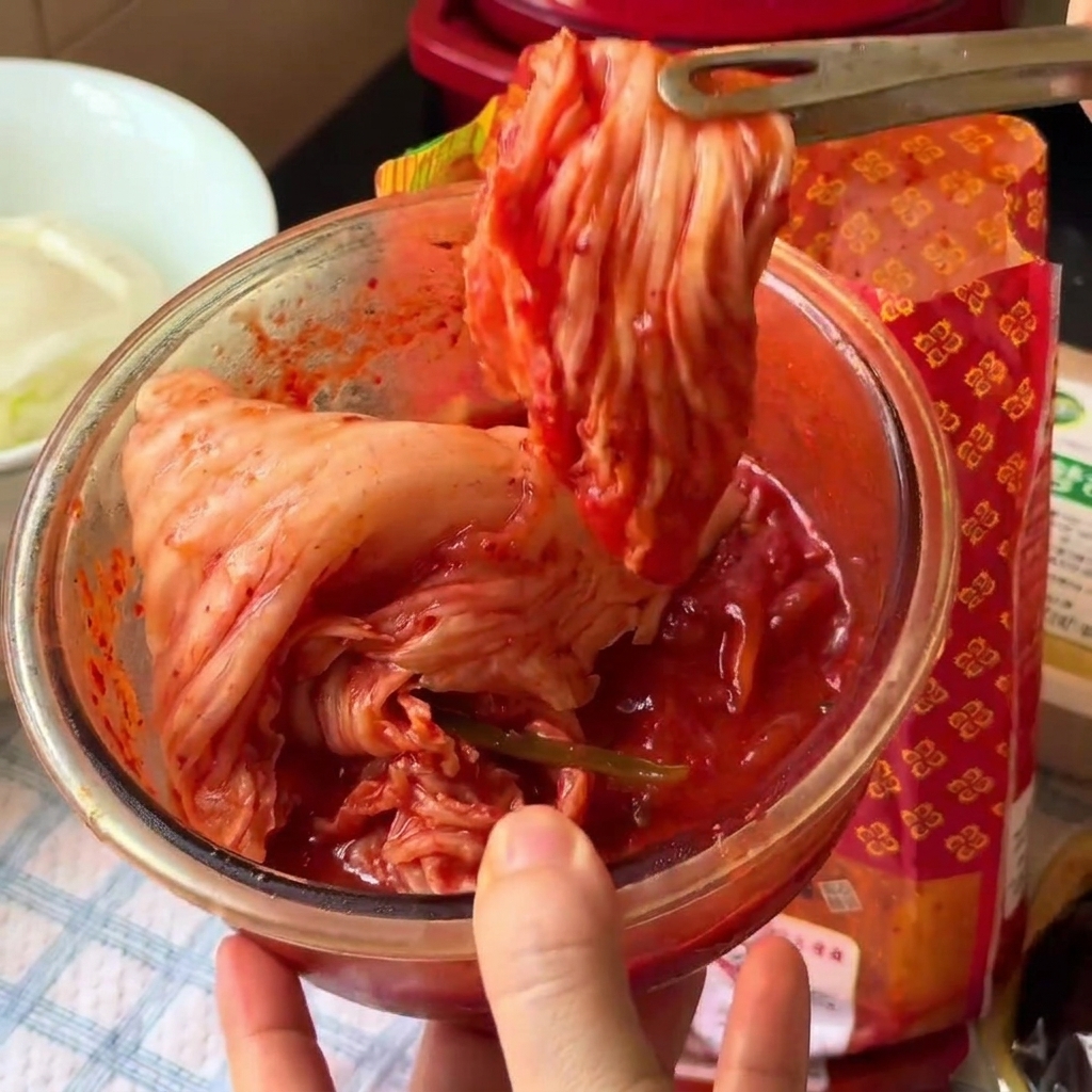 Le kimchi est coupé en petits morceaux à lintérieur dun bol en verre à laide de ciseaux de cuisine.