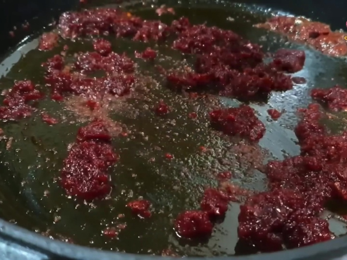 De petits morceaux de porc mélangés et sautés dans une poêle avec un mélange rouge vif dhuile et de piment.