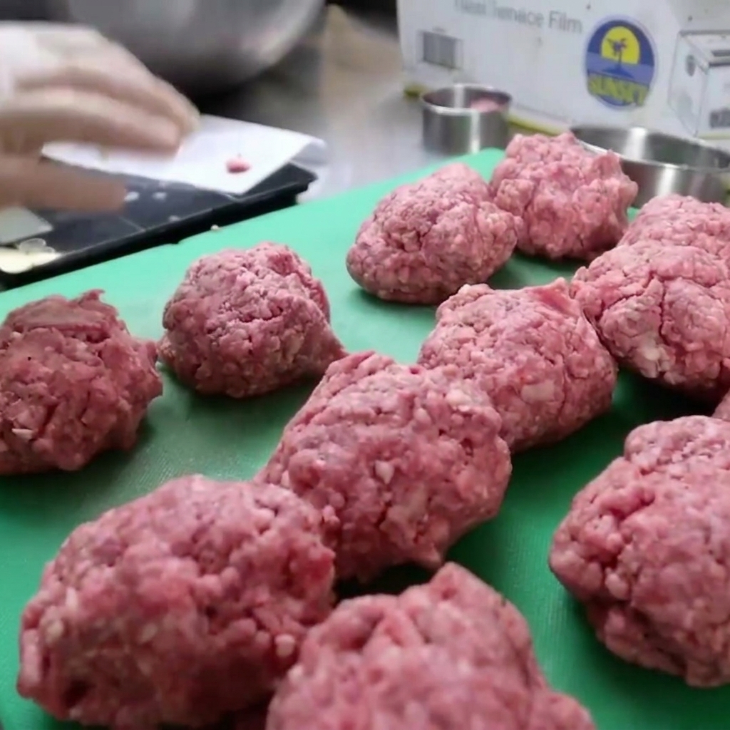 Viande de bison hachée tassée dans un moule circulaire pour former des steaks de burger épais.