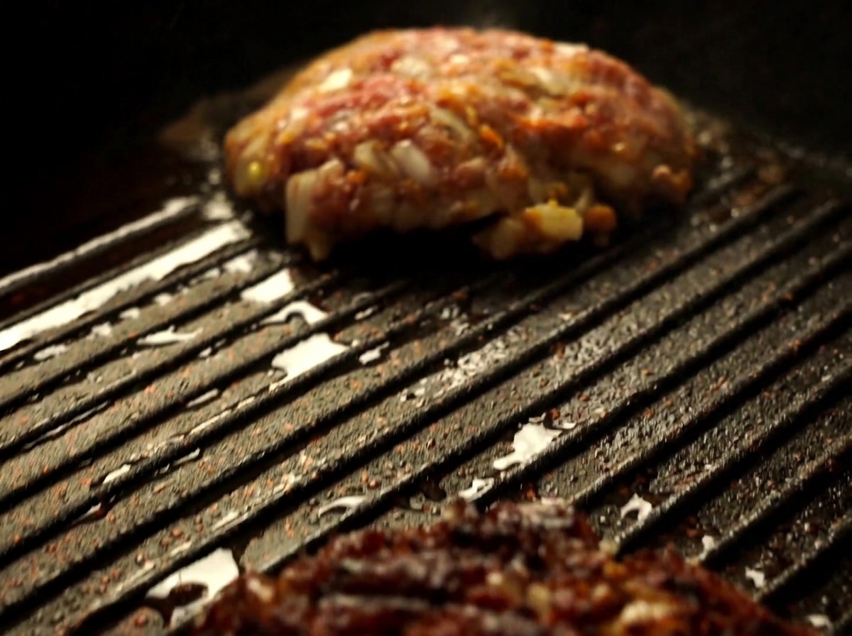 Gros plan sur un steak de Wagyu retourné à laide dune spatule dans une poêle grill chaude.