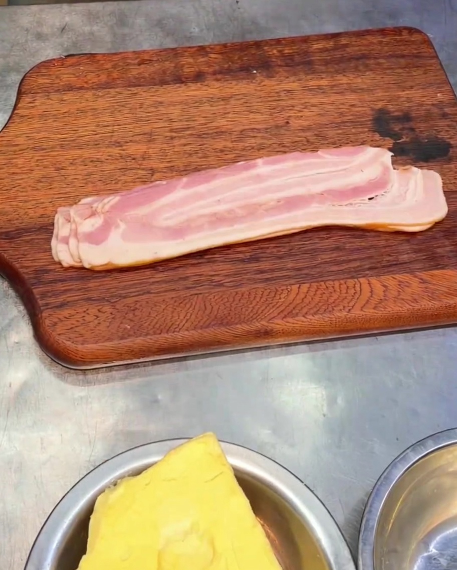 Morceaux de bacon fumé tranché reposant sur une planche à découper en bois.