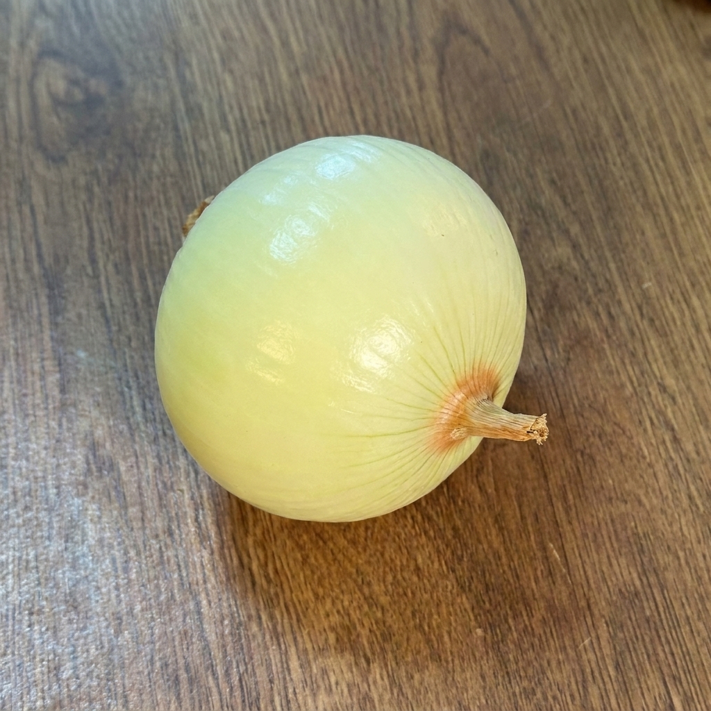 Un oignon entier pelé posé sur une surface en bois.