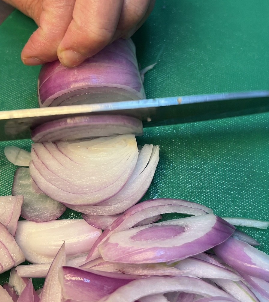 Oignons soigneusement tranchés sur une planche à découper verte.
