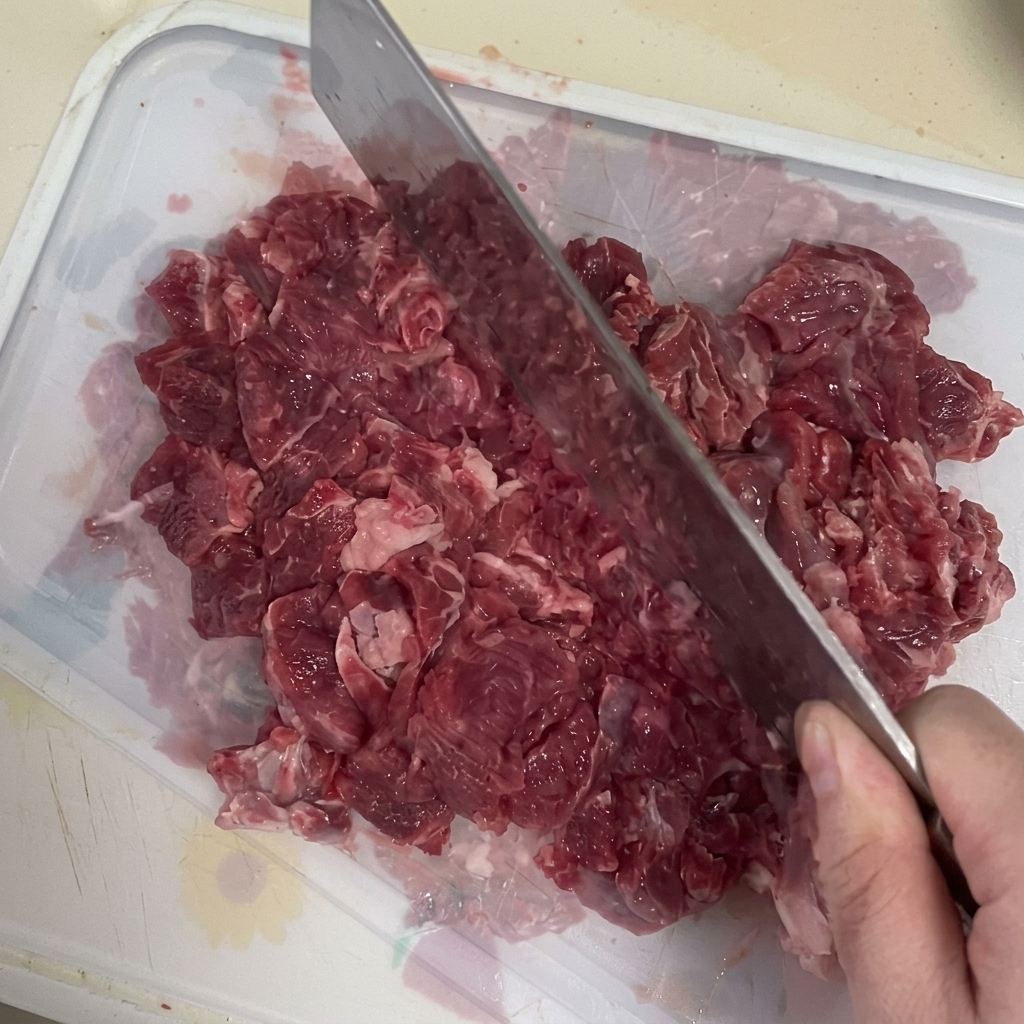 Un hachoir utilisé pour émincer du bœuf frais sur une planche à découper.
