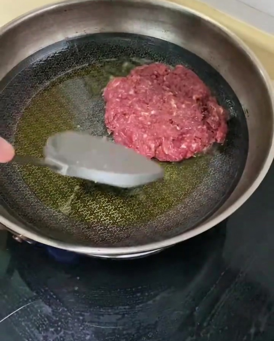 Un steak de bœuf assaisonné en train de frire dans une poêle chaude avec de lhuile.
