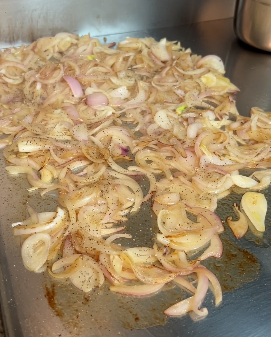 Oignons en train de caraméliser sur une plancha, assaisonnés dune pincée de poivre noir et de paprika doux hongrois vibrant.