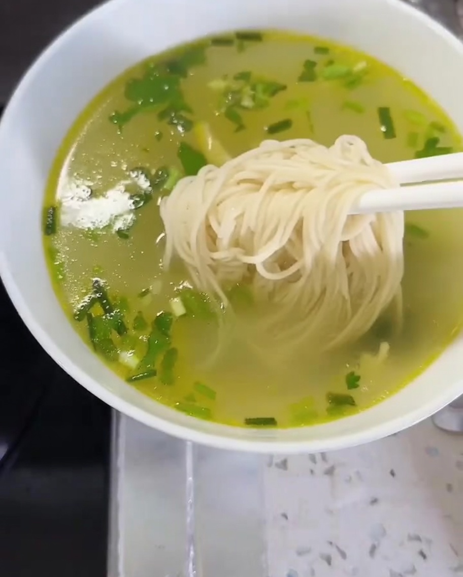 Nouilles et légumes transférés dans un bol de bouillon pour compléter le plat.