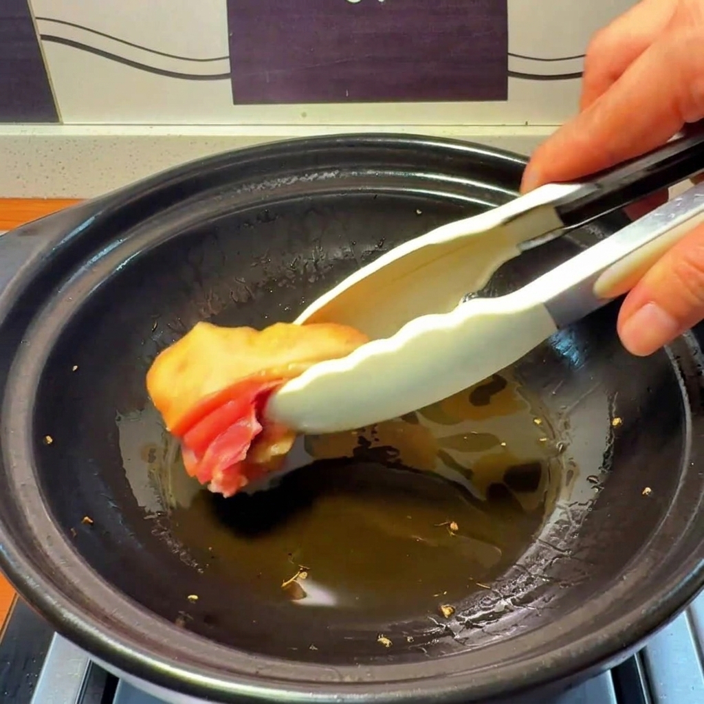 Morceaux de poulet cru ajoutés dans la marmite avec lhuile infusée au gingembre.