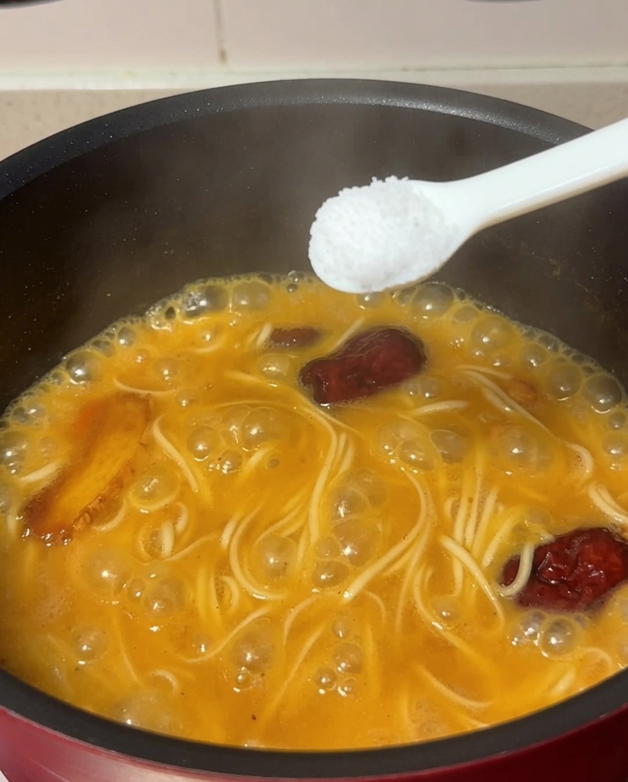 Une cuillère de sel ajoutée dans la casserole contenant les nouilles et la soupe.