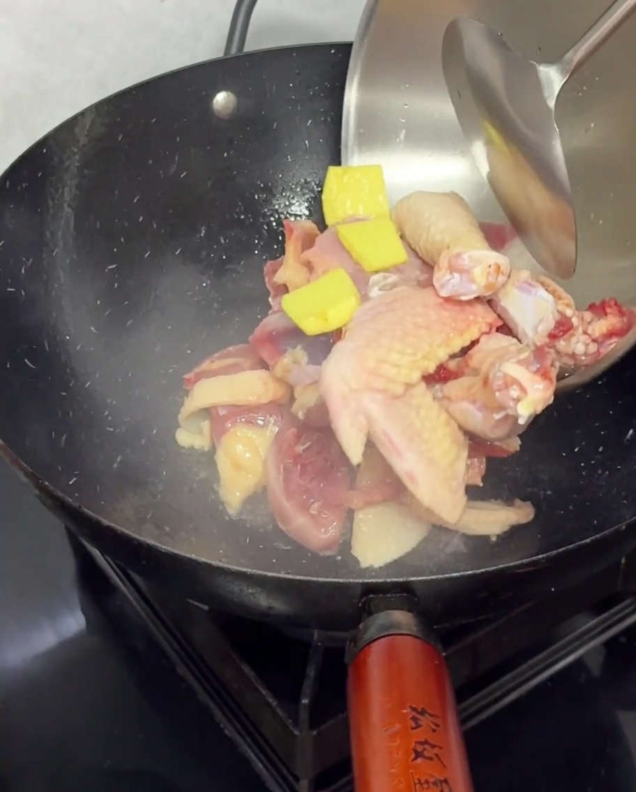 Morceaux de poulet frais et tranches de gingembre dans un wok chaud pour la saisie.