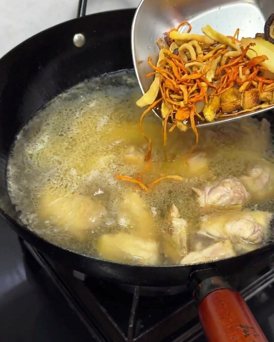 Ajout de champignons séchés réhydratés dans le bouillon de poulet frémissant.
