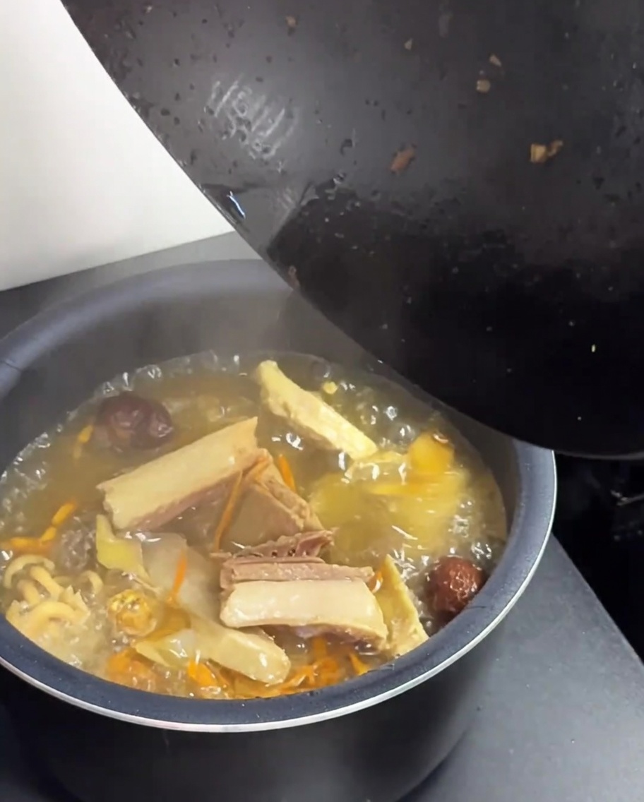 Transfert du poulet et du bouillon du wok vers la cuve du cuiseur à riz.