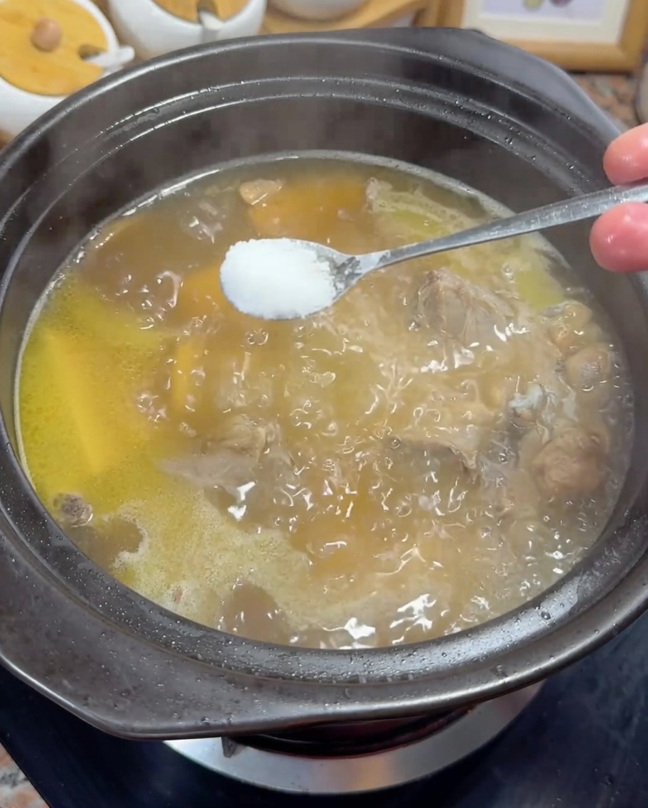 Ajout dune cuillère de sel dans un bouillon de poulet doré frémissant.