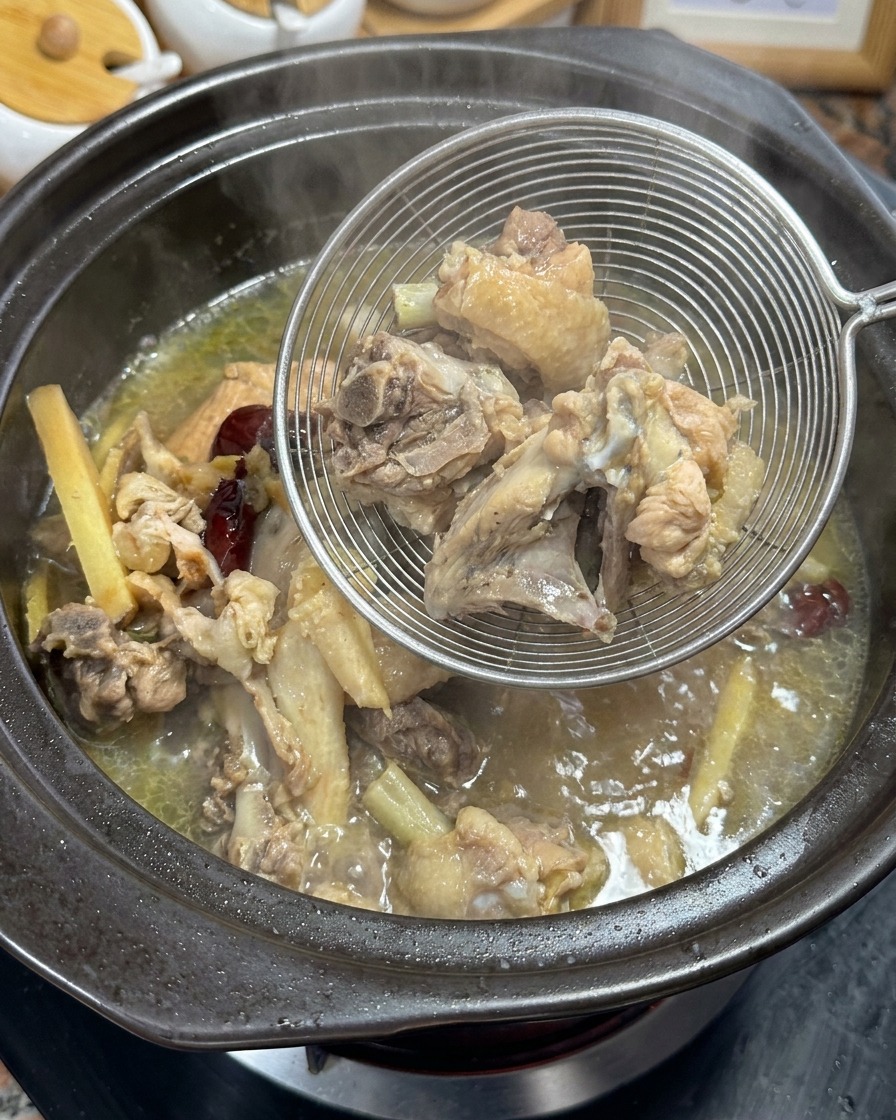 Retirer les os de poulet bouillis et les aromates du bouillon doré à laide dune écumoire.