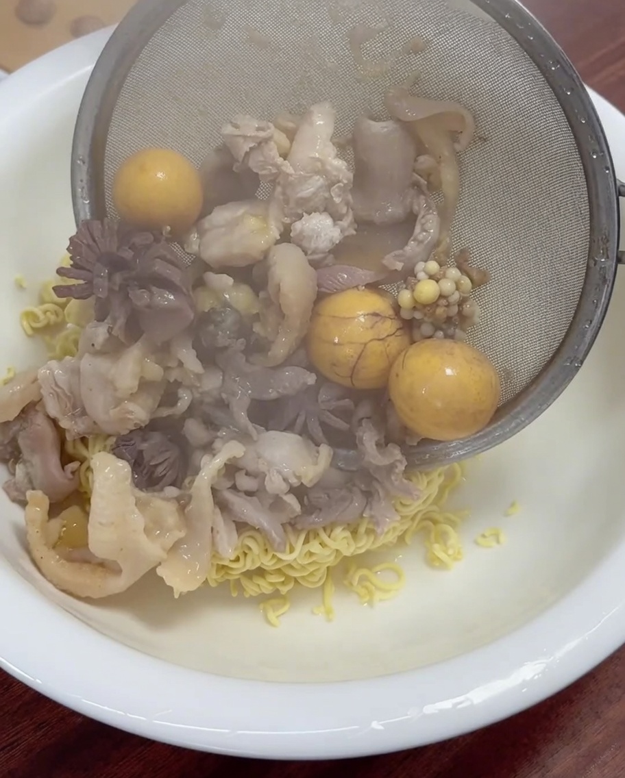 Viande de poulet et jaunes dœufs fraîchement cuits égouttés et placés dans un bol de nouilles.