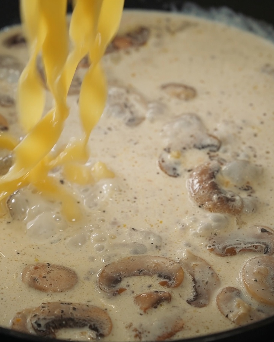 Pâtes et sauce à la truffe ajoutées à la poêle avec la sauce crémeuse aux champignons.