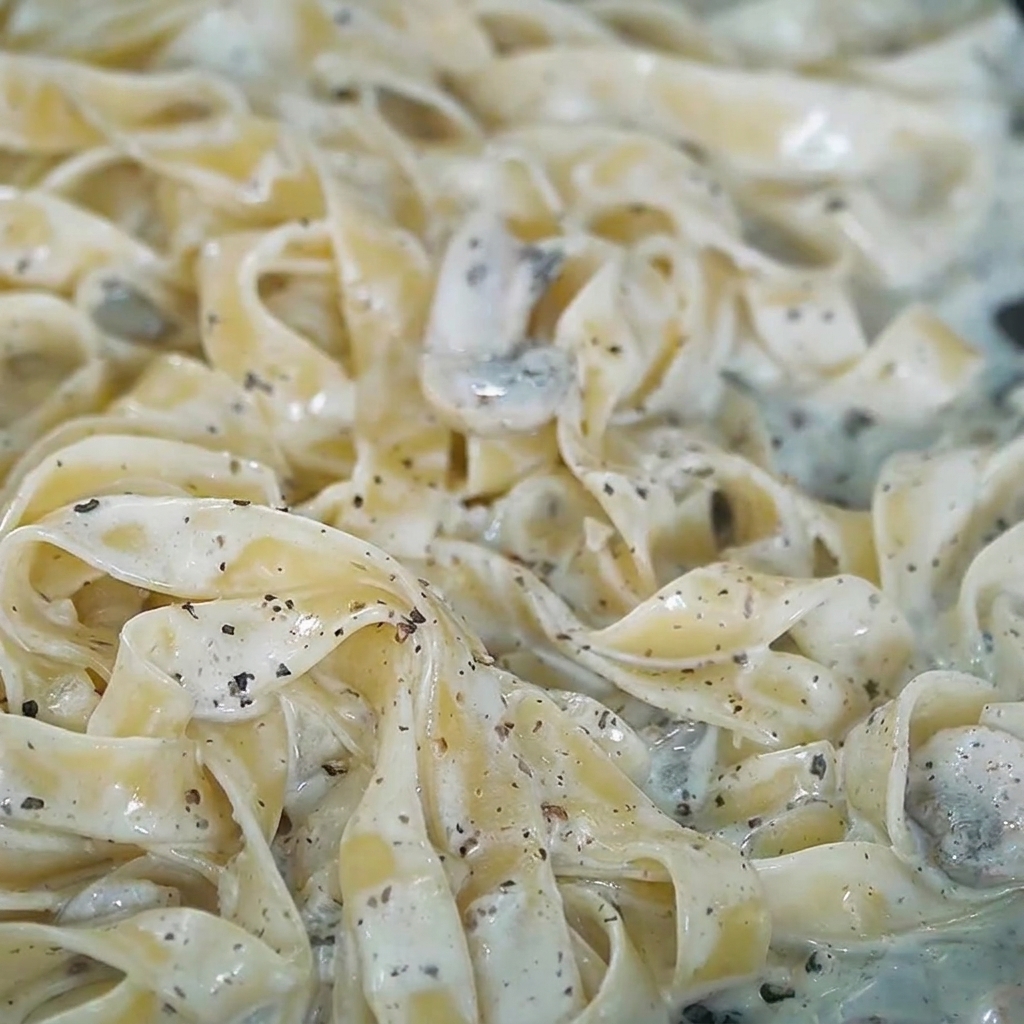 Sel et poivre noir fraîchement concassé saupoudrés sur les pâtes crémeuses à la truffe.