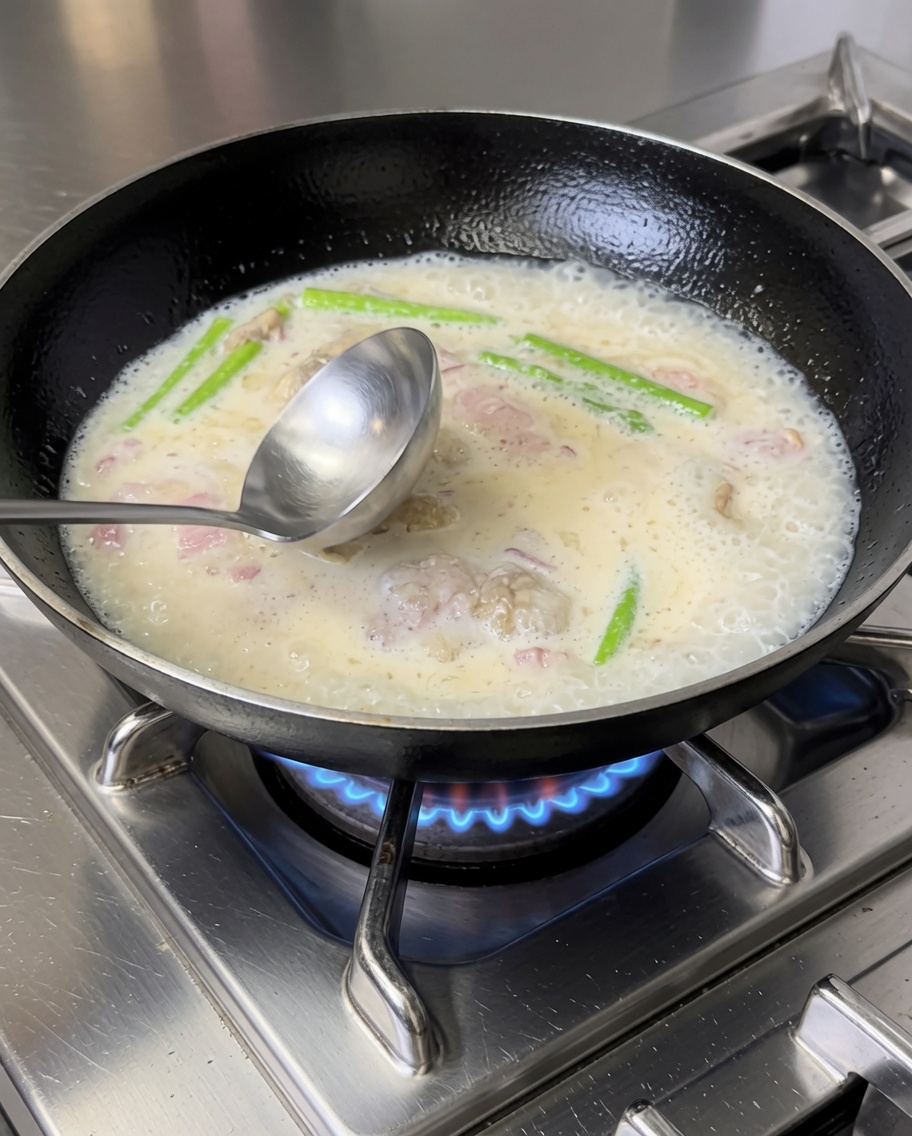 Pennes cuites mélangées à la sauce crémeuse au bacon et aux légumes dans une poêle.