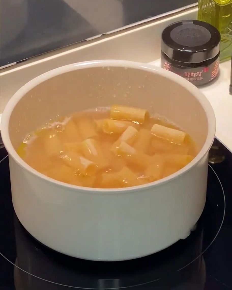 Rigatoni bouillonnant dans une casserole deau avec des gouttelettes dhuile en surface.
