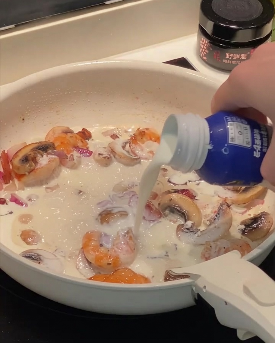 Crème et lait versés dans la poêle avec les autres ingrédients.