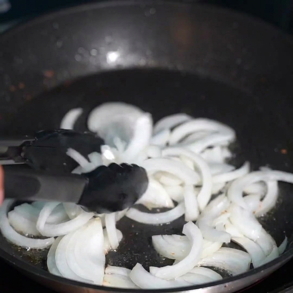 Oignons émincés devenant translucides dans le gras de bacon doré.