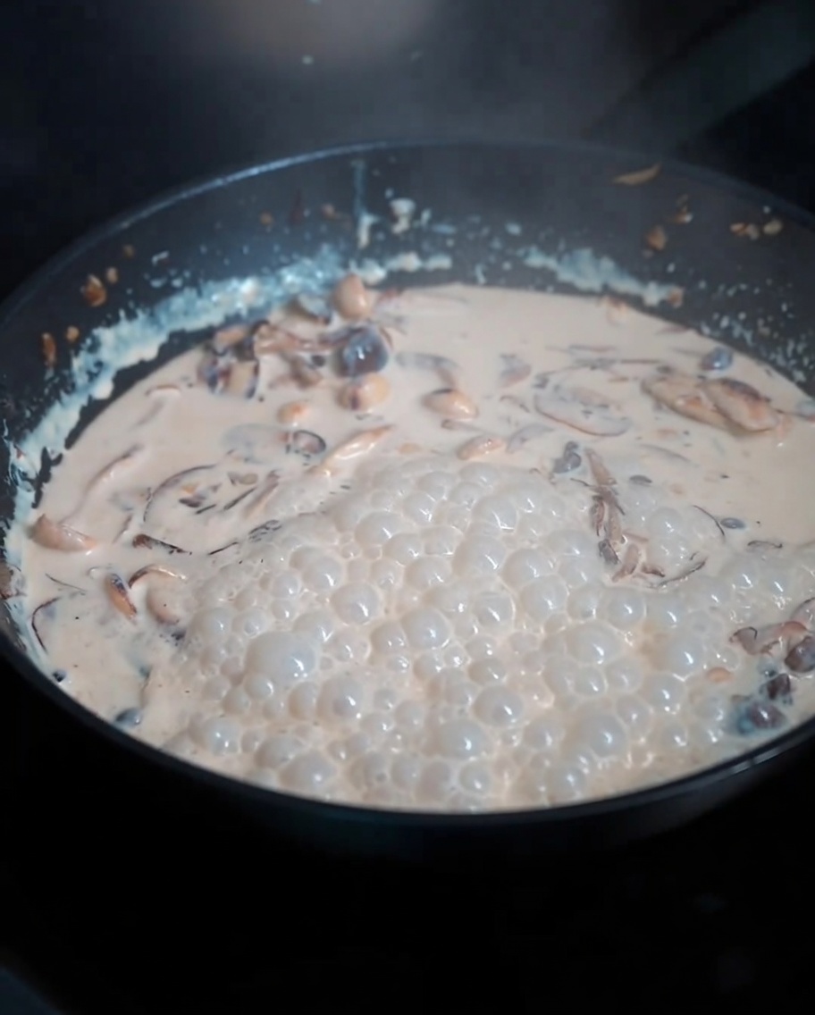 Pâtes cuites incorporées à la sauce crémeuse aux champignons.