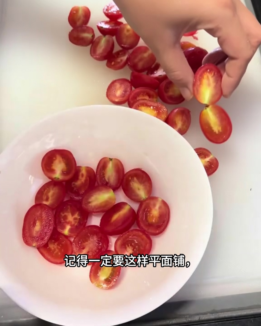 Gros plan sur des moitiés de tomates cerises soigneusement disposées en une seule couche dans un bol blanc.