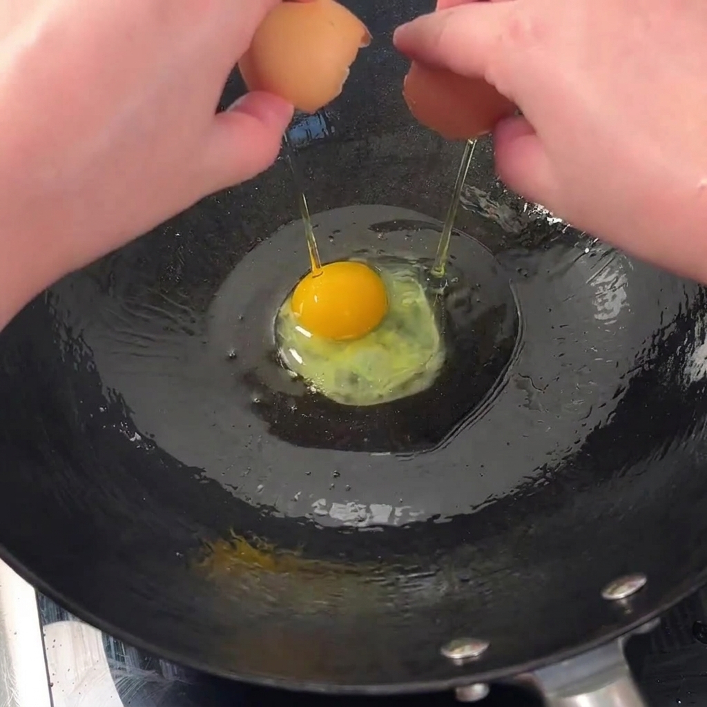 Deux œufs frais cassés qui grésillent dans un wok chaud et huilé pour obtenir des bords croustillants.