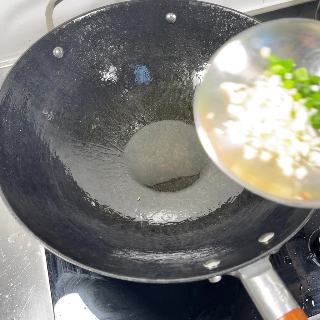 Oignons verts hachés et ail émincé ajoutés avec une louche dans un wok chaud contenant de lhuile.