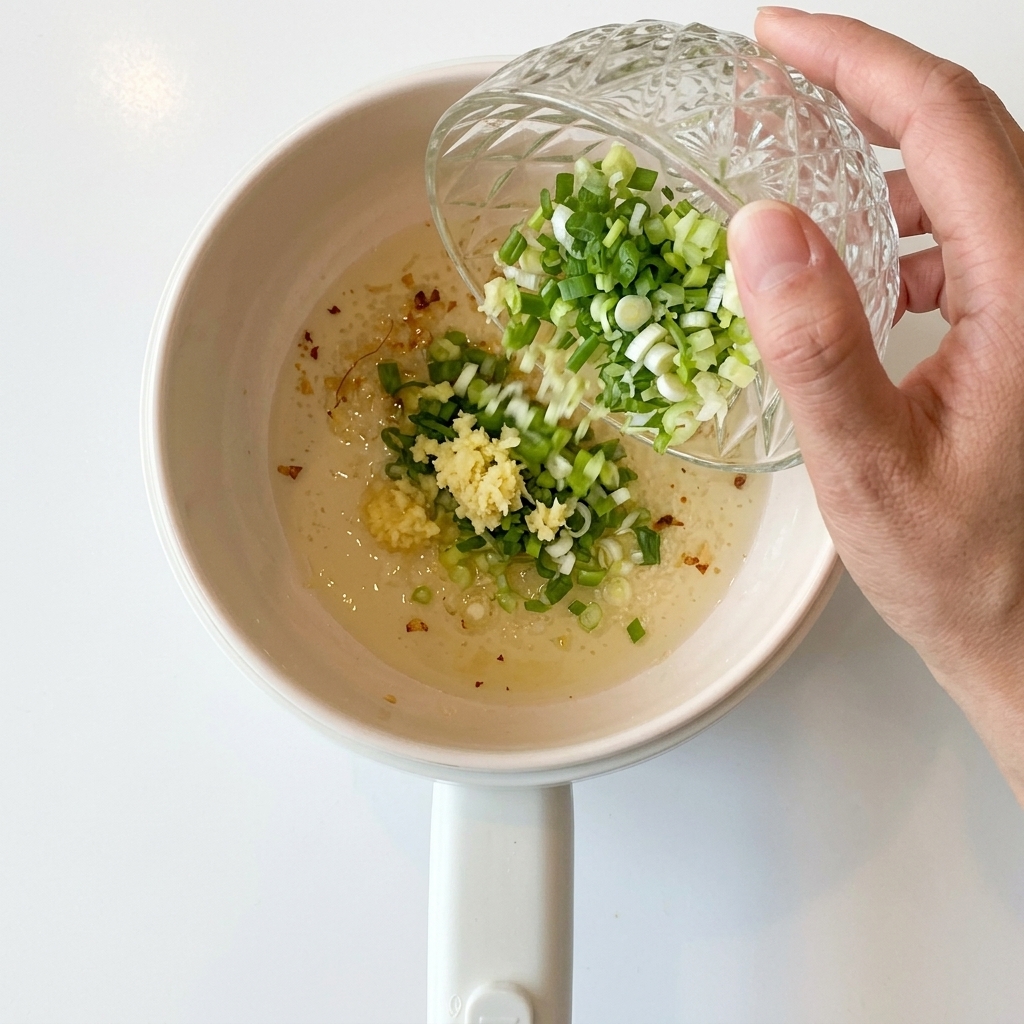 Oignons verts hachés versés dans la casserole avec lail sauté.