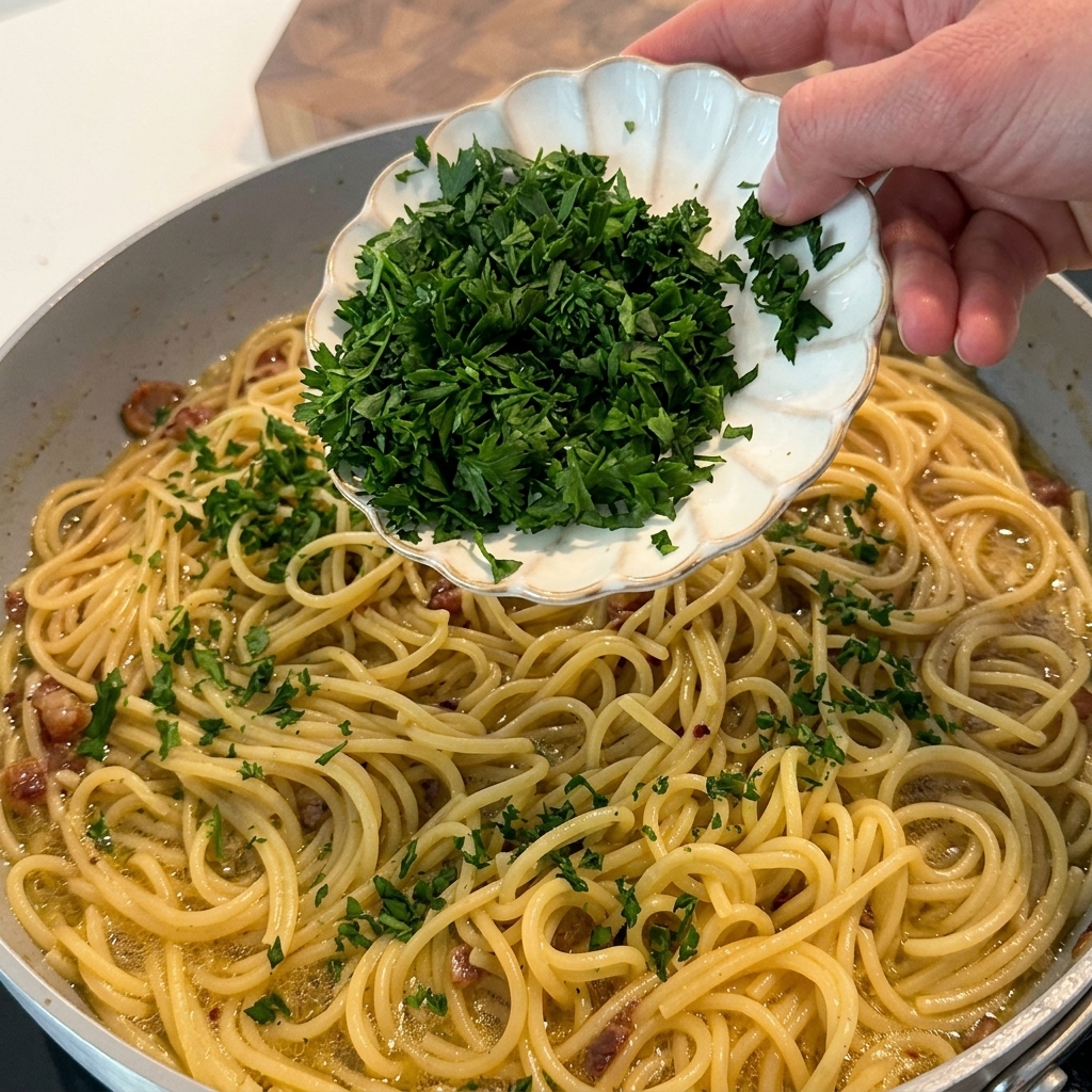Persil frais haché saupoudré sur les pâtes finies dans la poêle.
