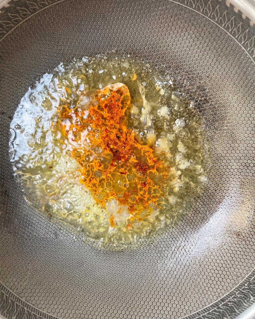 Piment en poudre saupoudré dans la sauce bouillonnante dans le wok.