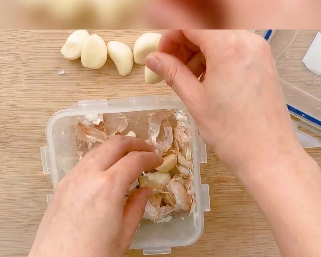 Gousses dail épluchées coupées en fines tranches sur une planche en bois.