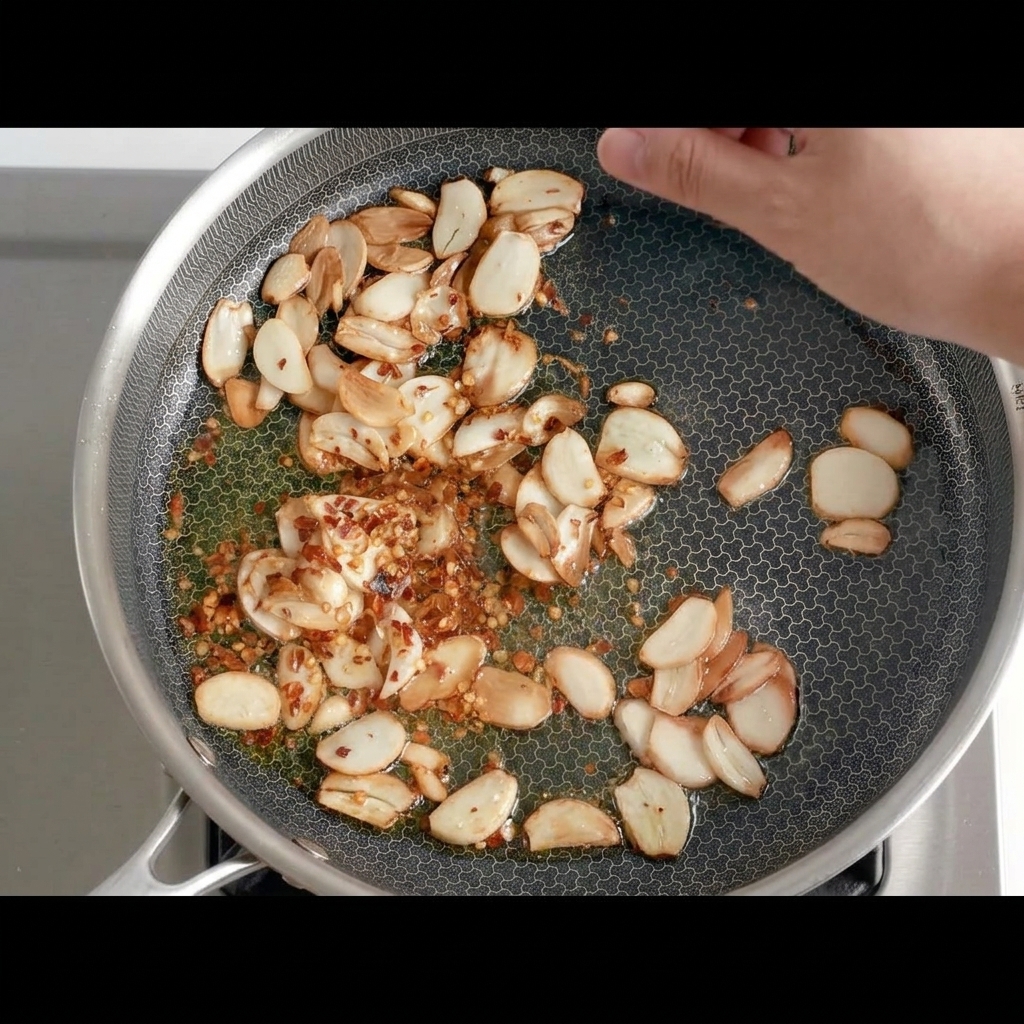 Morceaux de piment séché ajoutés dans la poêle avec lail frit doré.