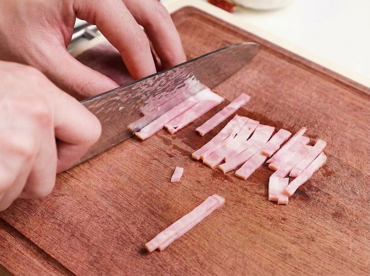 Fines tranches de bacon cru coupées sur une planche en bois.