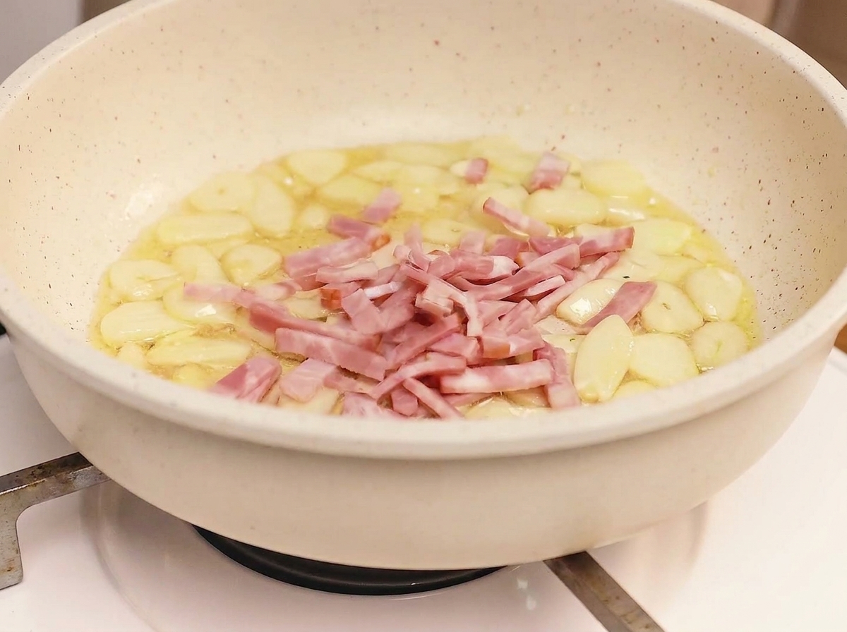 Bandes de bacon friant dans une poêle avec de lail, atteignant un état doré et croustillant.