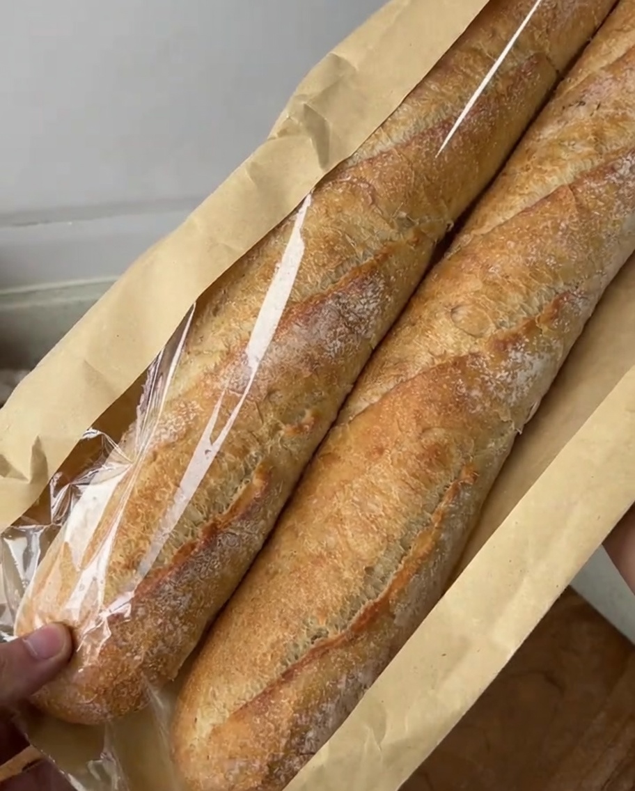 Tranches diagonales de baguette disposées sur une planche à découper, prêtes pour le mélange de beurre à lail.