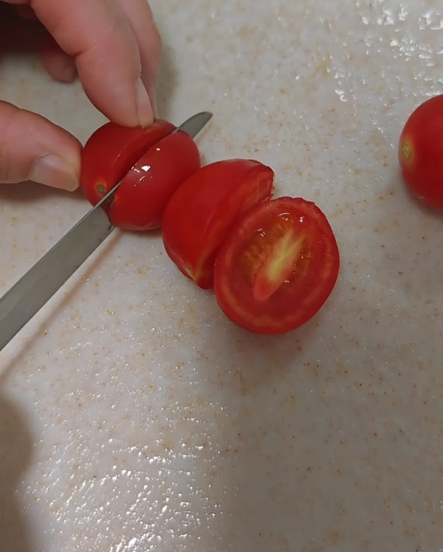Tomates cerises fraîches soigneusement coupées en deux sur une planche à découper.