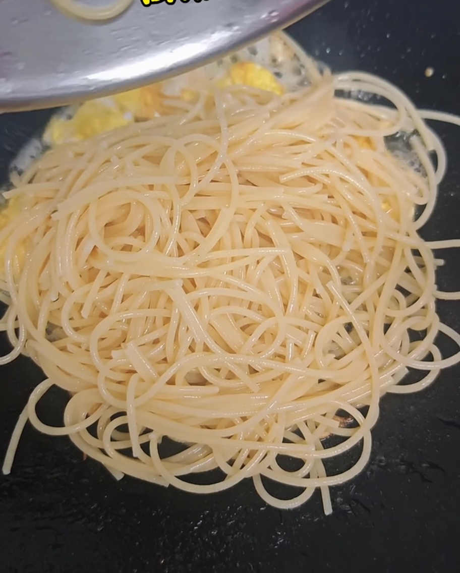 Fleurettes de brocoli blanchies et tomates cerises coupées en deux ajoutées dans le wok avec les spaghettis et les œufs.