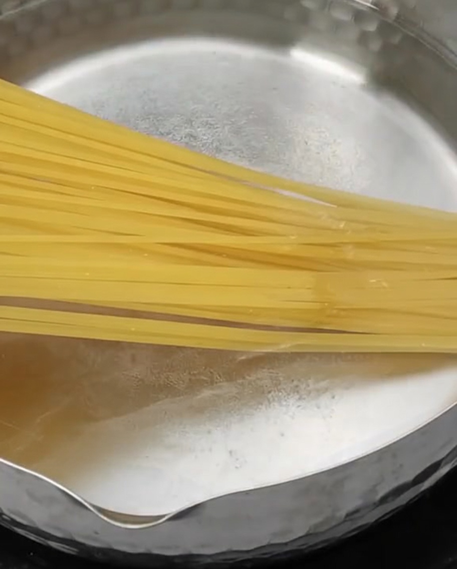 Pâtes longues sèches plongées dans une casserole deau bouillante.