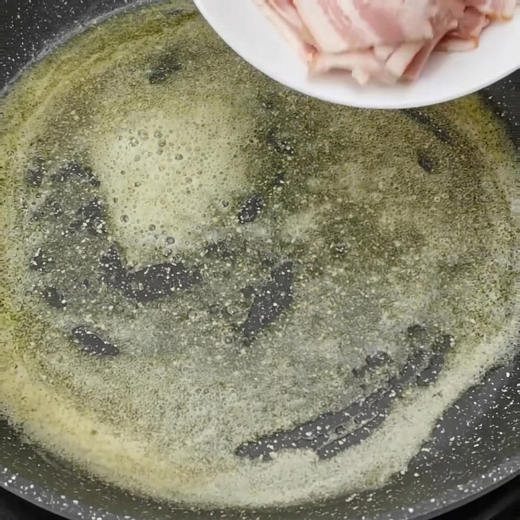 Morceaux de bacon cru ajoutés dans la poêle avec le beurre fondu.