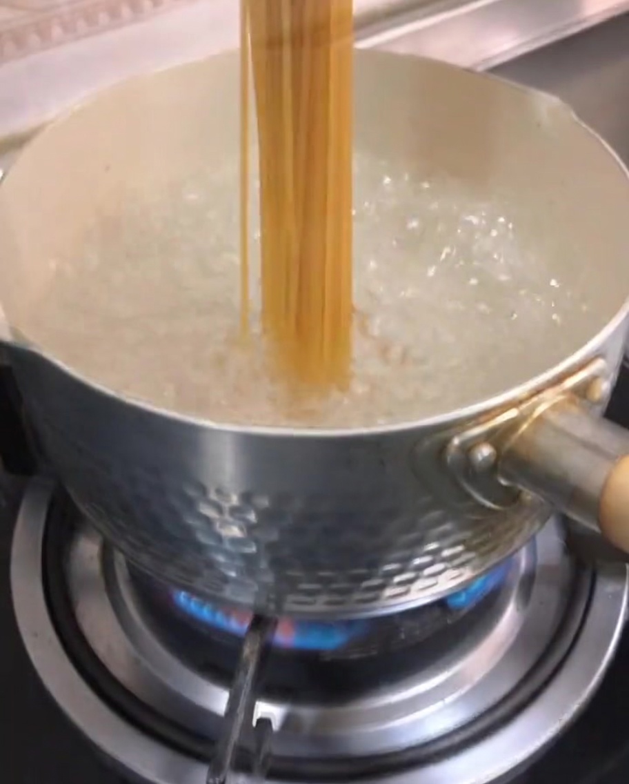 Spaghetti secs plongés dans de leau bouillante.
